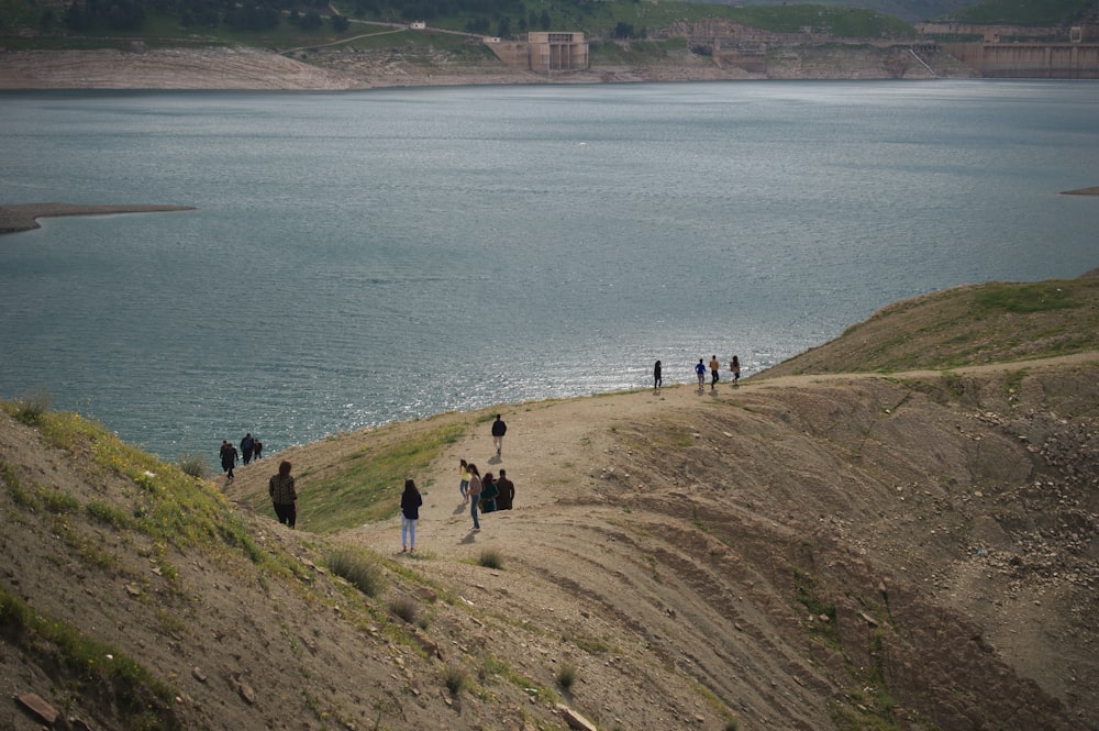 a group of people walking on a path by a body of water