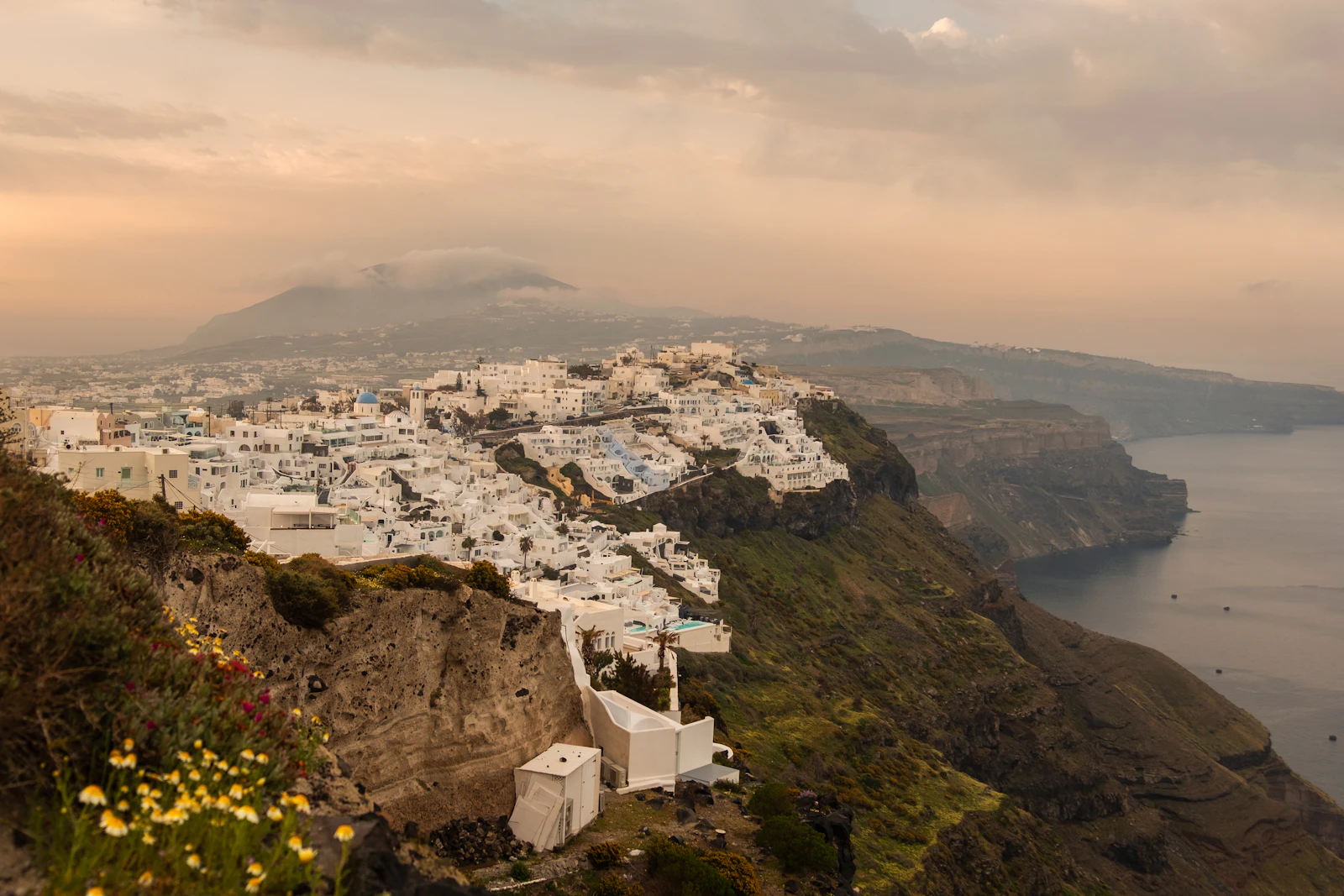 White cliffside buildings along Santorini's caldera edge at golden hour