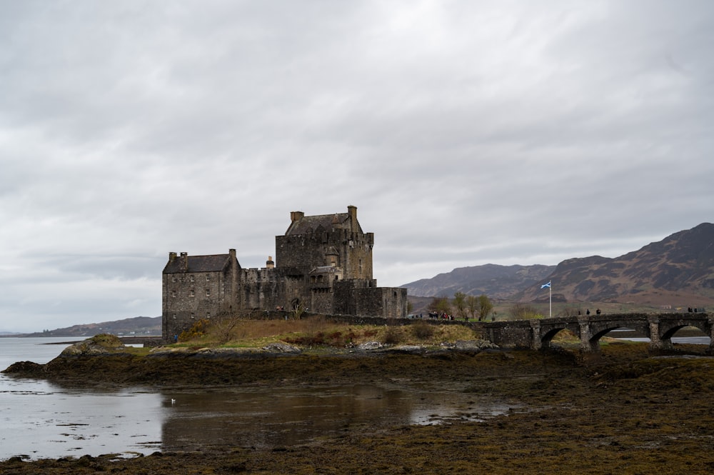 a castle on a hill by a river with Eilean Donan in the background