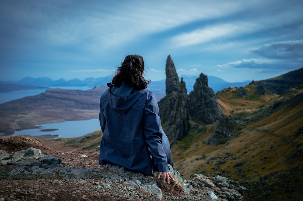 a person sitting on a rock overlooking a lake and mountains