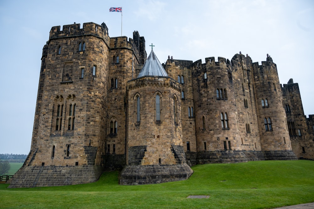 a castle with a flag on top with Alnwick Castle in the background
