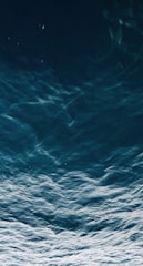 Dark, deep ocean waves ripple and flow with a sense of motion and depth, creating a mesmerizing pattern on the water's surface.