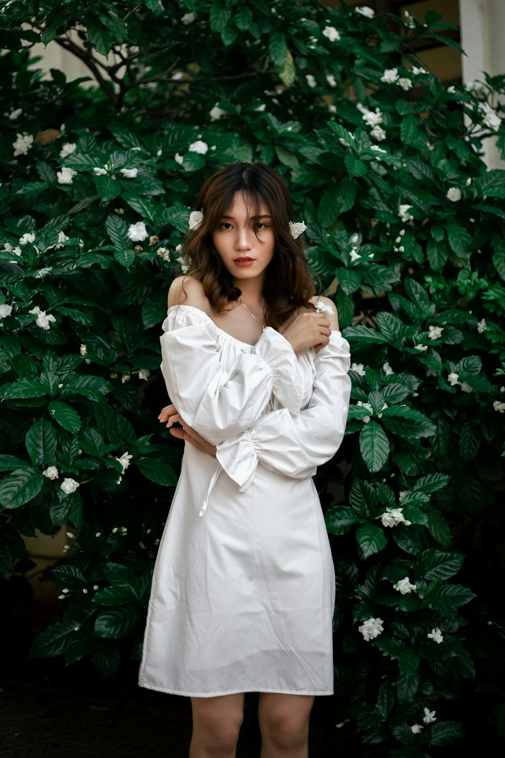 a woman posing in front of a bush