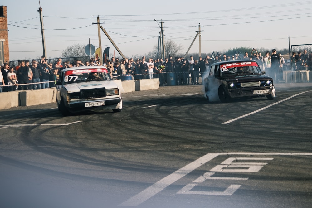 a couple of race cars on a race track with a crowd watching