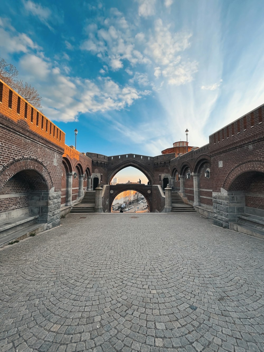 a stone walkway with a stone walkway and a stone wall with a blue sky and clouds