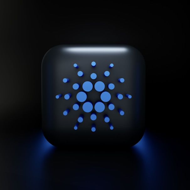 A digital, stylized design featuring a square-shaped object with rounded edges, displaying a symmetric arrangement of various-sized blue circles on its surface, set against a dark background.