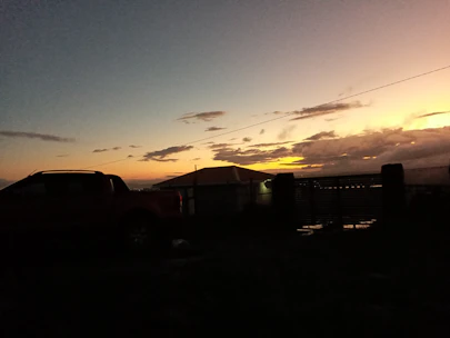 A rugged truck parked against a dusk sky blending deep orange and charcoal hues.