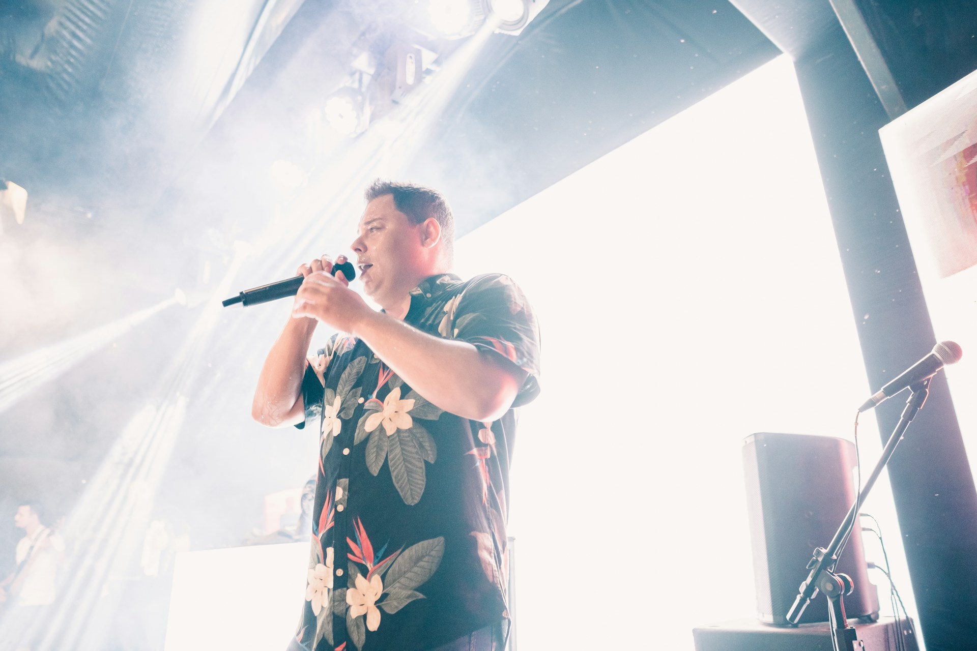 Chris Herden performing passionately on stage under warm spotlight, dressed in classic suit with vintage microphone.