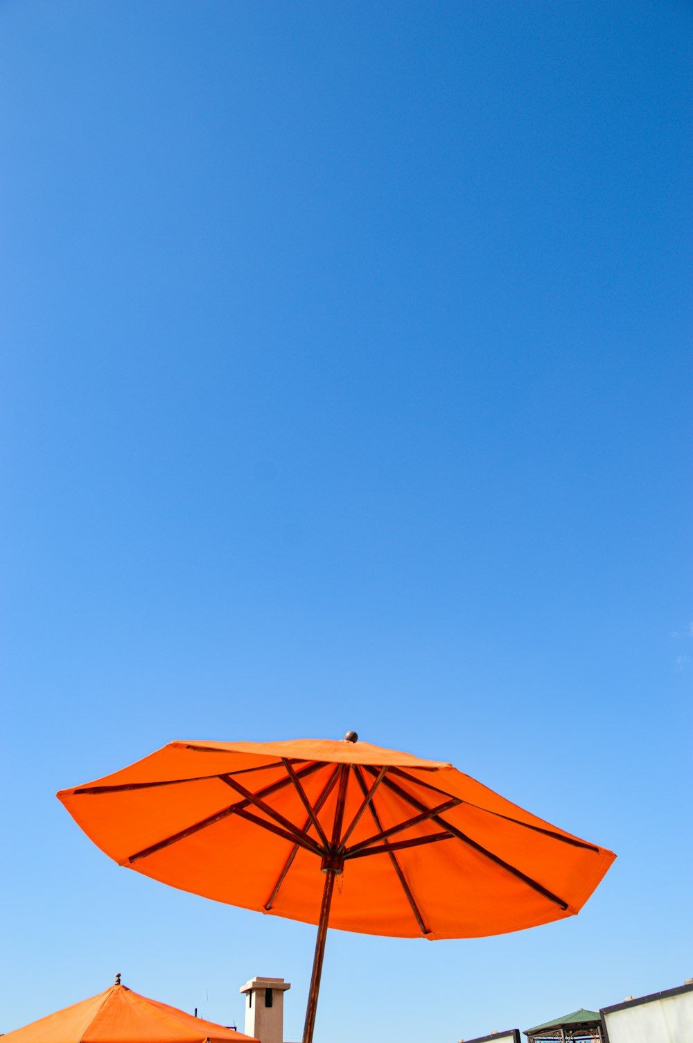 Ein orangefarbener Regenschirm unter blauem Himmel