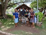 A group photo of members standing proudly in front of a lush green backdrop.