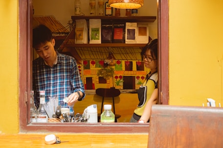 Store employee assisting a customer with beverage selections in a cozy local shop.