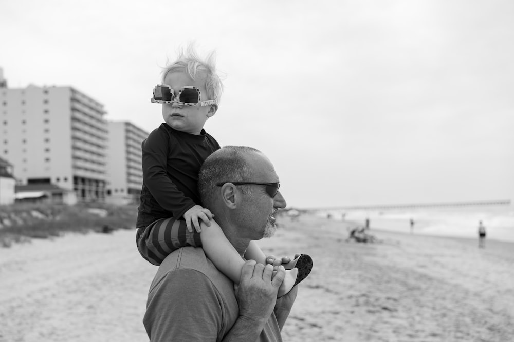 a man holding a baby on a beach