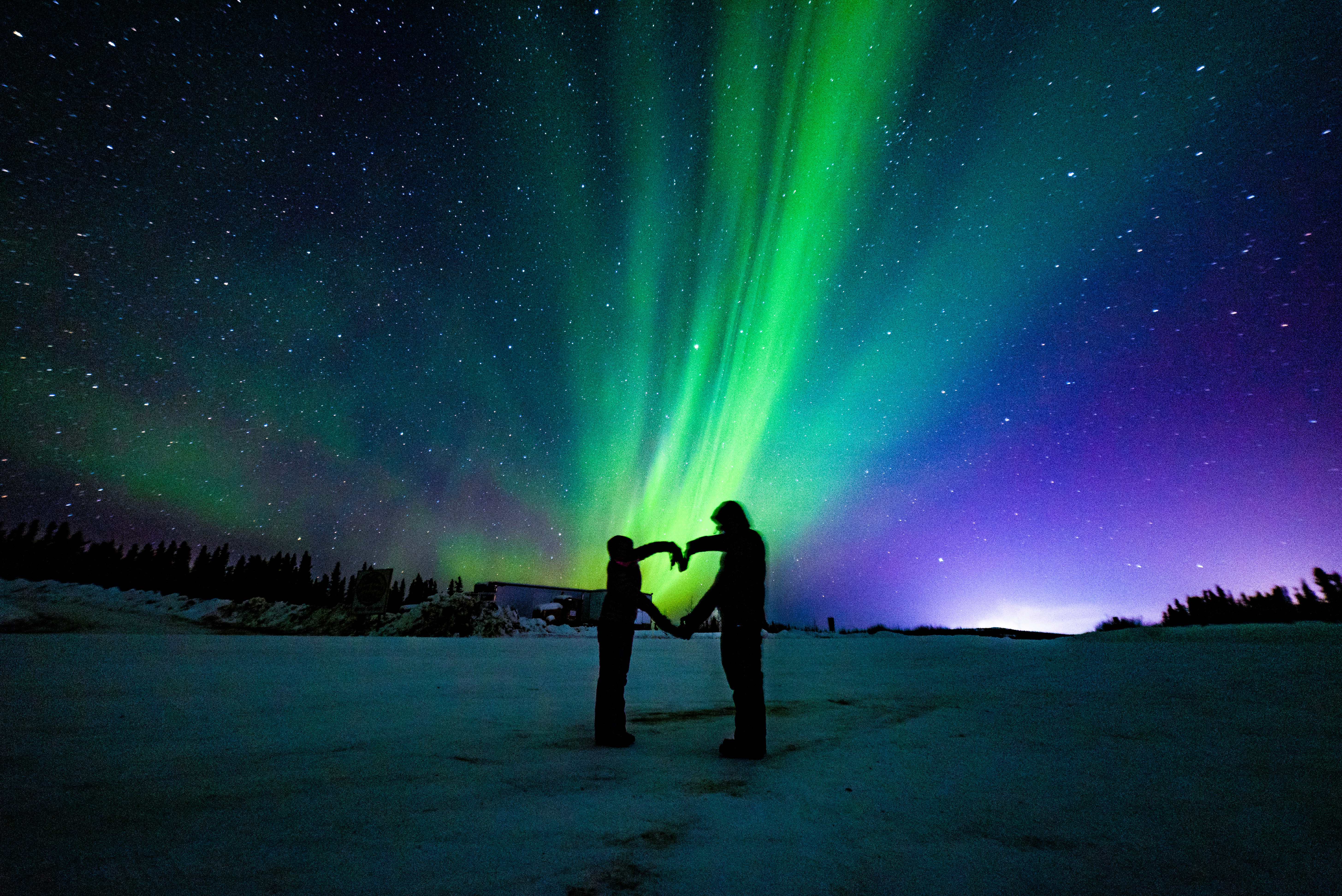 a couple of people holding a yellow object in front of a starry sky