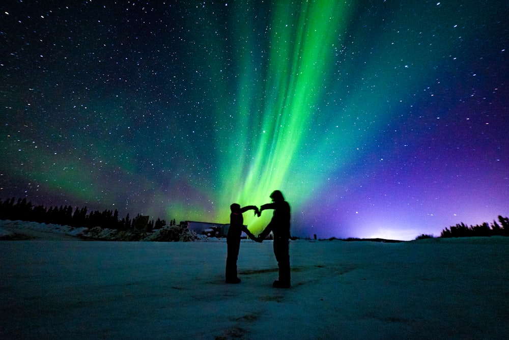 a couple of people holding a yellow object in front of a starry sky