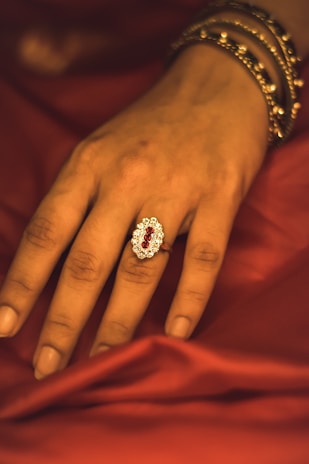 Hand wearing a unique statement ring featuring a large, eye-catching artificial jewel.