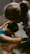 Two people appear to be engaged in a soothing, intimate moment, possibly involving support or care. One person is in a tub of water, with their head resting on their arms, while the other person leans over from outside the tub, gently touching and comforting them.
