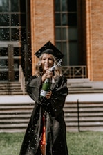 a woman in a graduation gown and cap holding a bottle of water