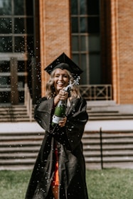 a woman in a graduation gown and cap holding a bottle of water