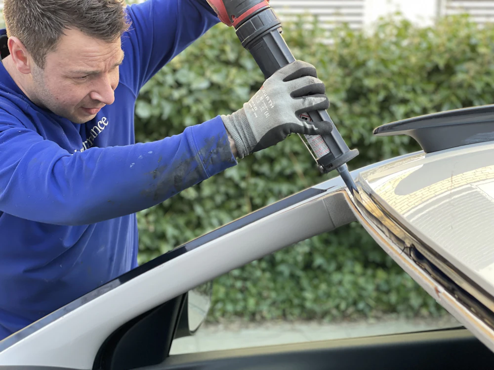 Auto glass technician applying urethane adhesive to a windshield frame before installing new glass