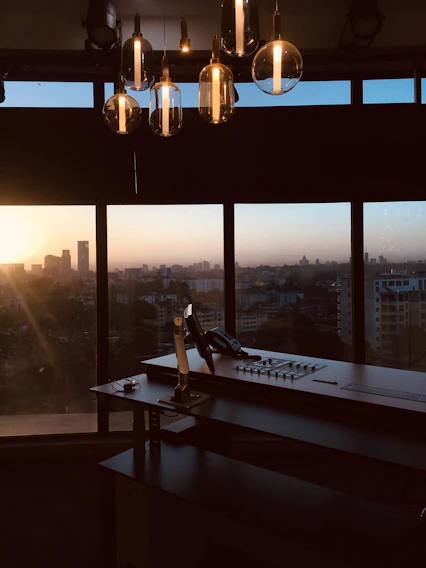 A sleek, minimalist office space with a large window overlooking a city skyline at dusk.