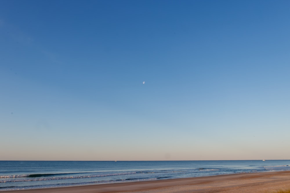 a beach with a body of water and a blue sky