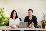 a man and a woman sitting at a table with a laptop