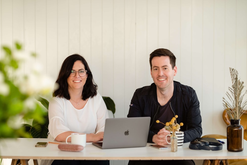 a man and a woman sitting at a table with a laptop