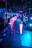 A bustling city street filled with various modern cars and neon lights at night.