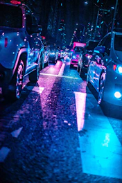 A futuristic city street at night with neon-lit cars representing urban mobility.