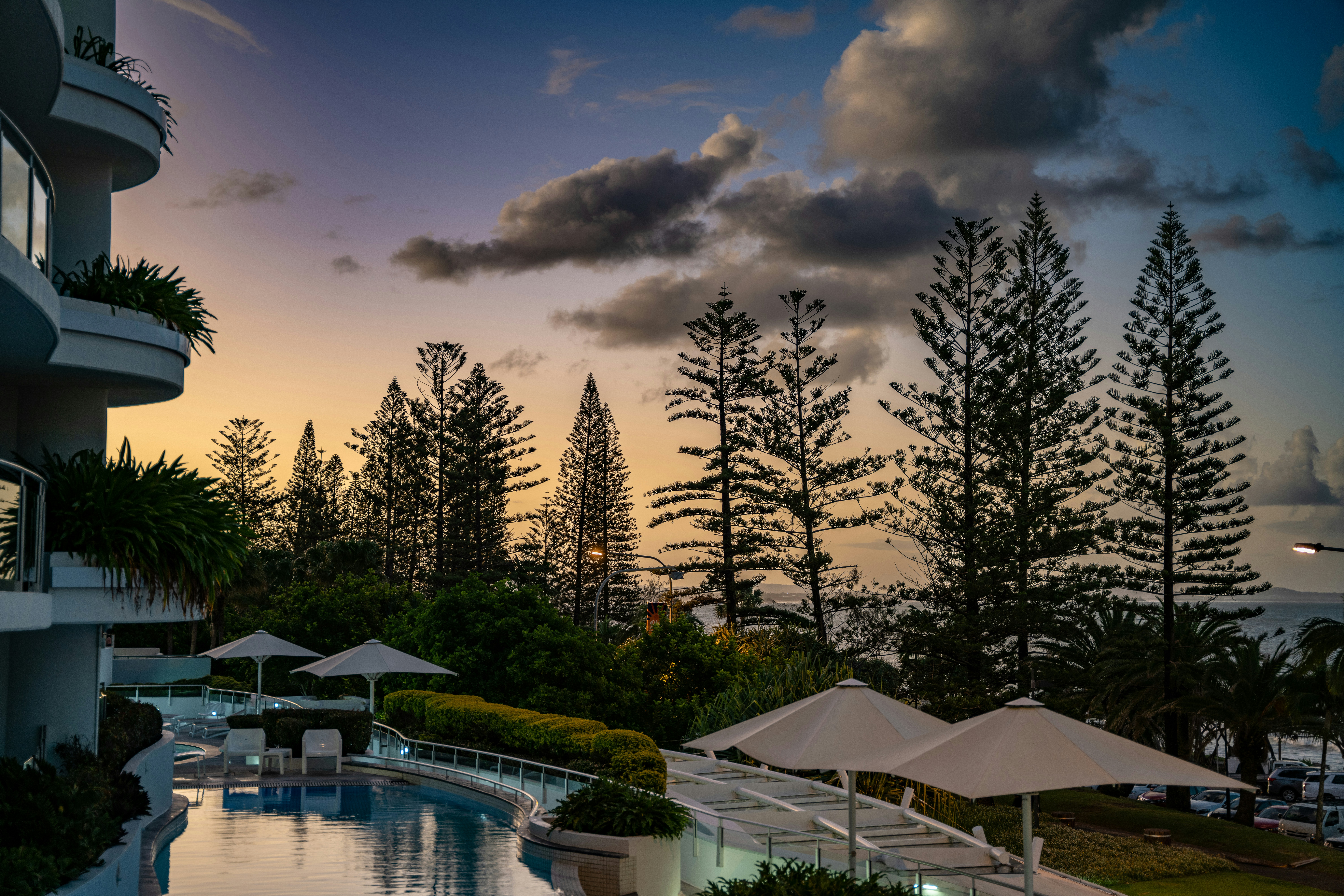 a pool with umbrellas and trees by it