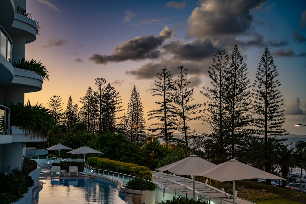 a pool with umbrellas and trees by it