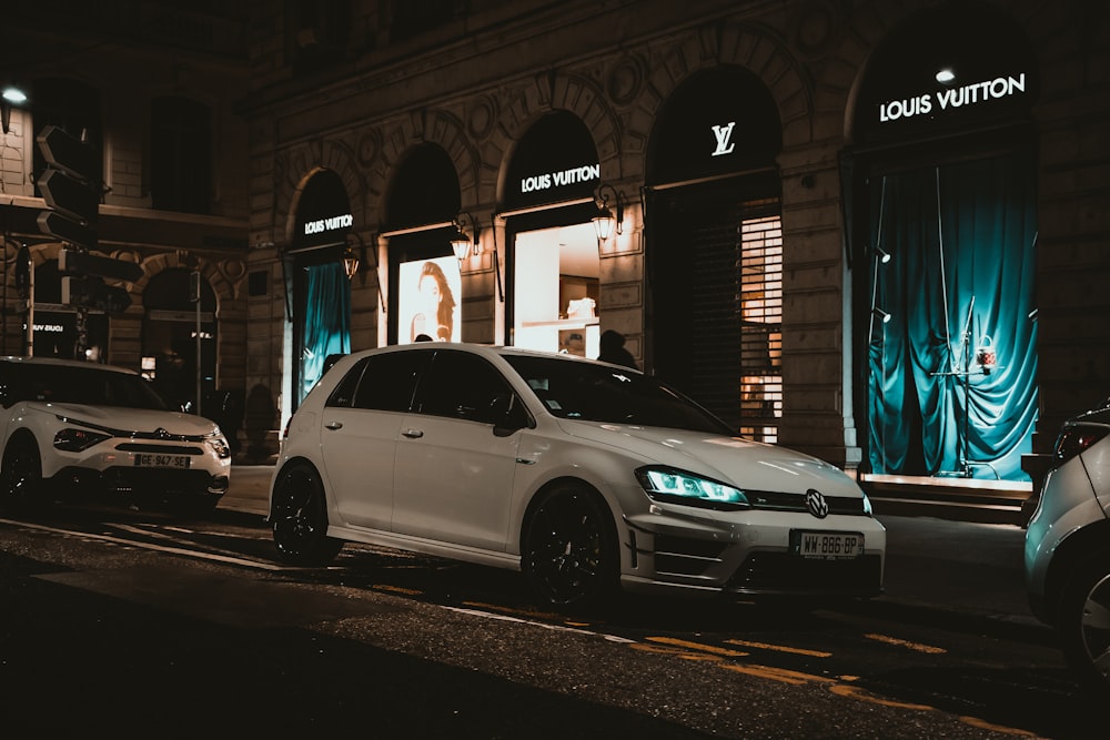 a white car parked in front of a building with a blue curtain