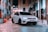 a white car parked on a brick road between buildings