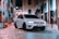 a white car parked on a brick road between buildings