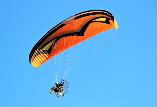 Paramotor pilot navigating a coastal route with a vibrant advertising banner.