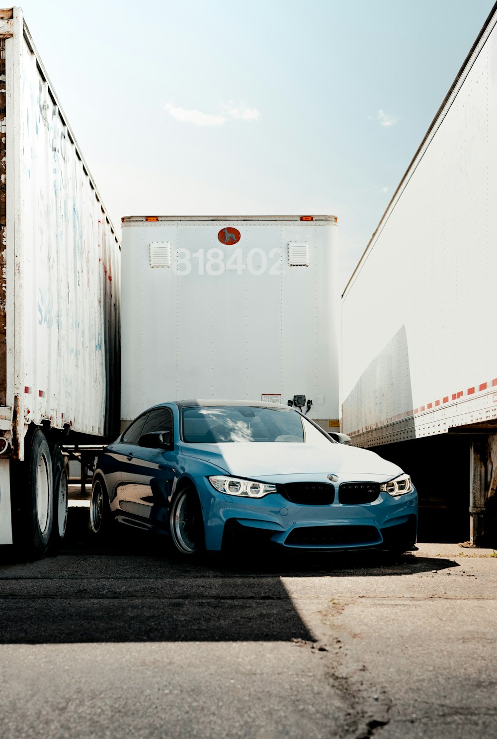 a blue car parked in front of a shipping container