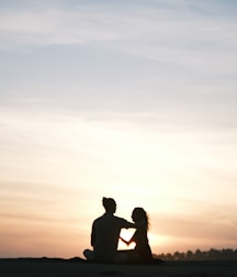 A couple relaxing on a tropical beach during sunset.