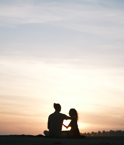 Couple enjoying a sunset on a tropical beach with palm trees.