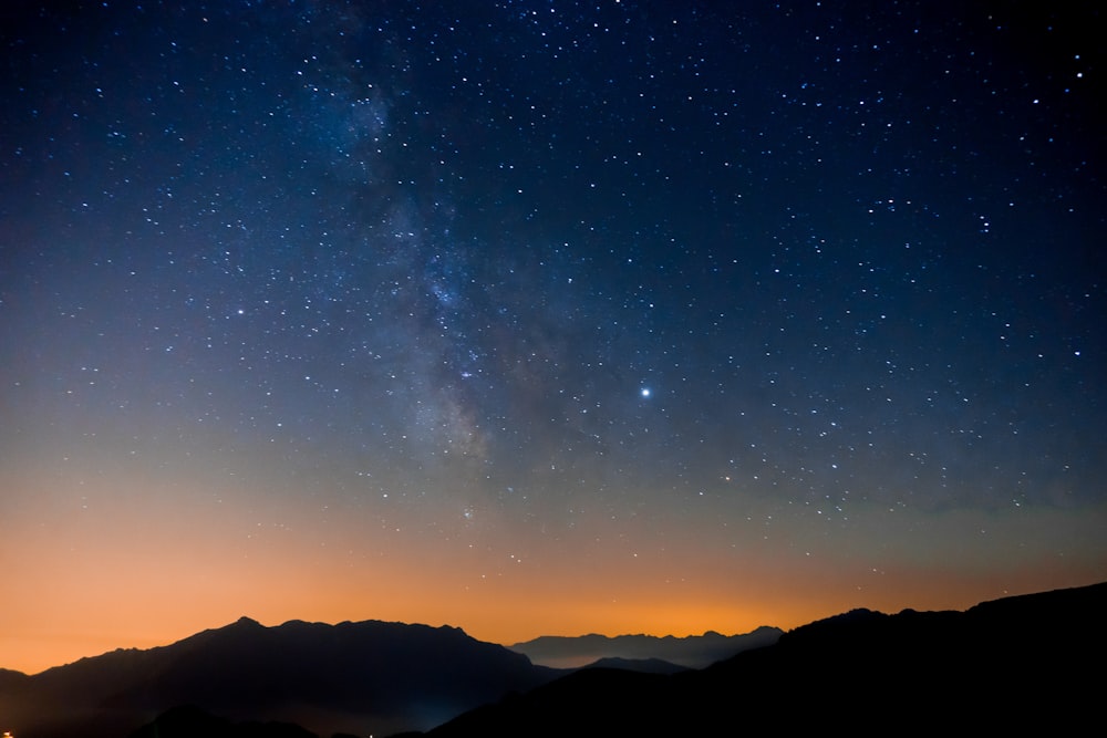 a starry night sky over mountains