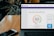 A laptop displays a credit score website with a score of 825, labeled as excellent, set on a wooden table with a smartphone nearby. Dark leafy plant elements are blurred in the background.