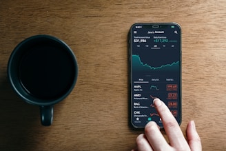 a hand holding a phone next to a cup of coffee