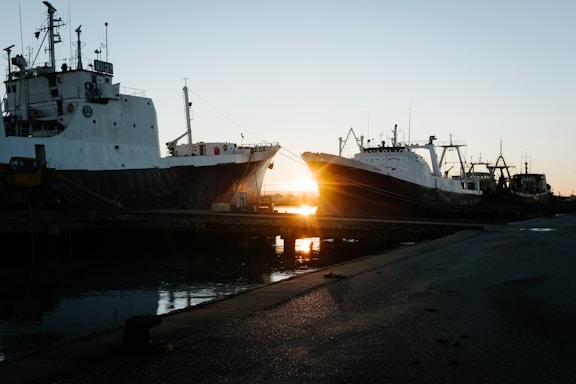 A calm harbor at sunset with ships docked, reflecting Goldenstone's steady marine management.