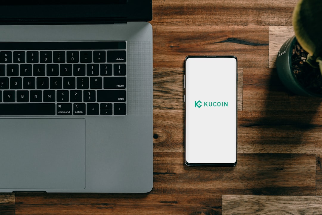 a cell phone next to a laptop, Kucoin Crypto Exchange</p>
<p>