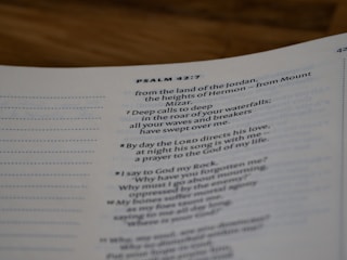 A close-up view of a page from a Bible open to Psalm 42:7. The text is focused on verses discussing spiritual themes, with some text in bold for emphasis. The page has a clean, white background with neatly printed black text.