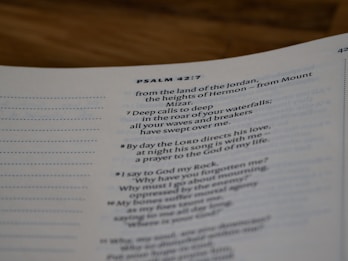 A close-up view of a page from a Bible open to Psalm 42:7. The text is focused on verses discussing spiritual themes, with some text in bold for emphasis. The page has a clean, white background with neatly printed black text.