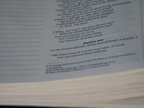 A close-up view of a page from the Bible, displaying text from the book of Psalms. The foreground features Psalm 44, with some of the text in italics. The left side displays dotted lines meant for note-taking.