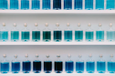 a group of blue bottles on a white shelf