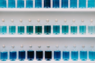 a group of blue bottles on a white shelf