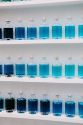 a group of blue bottles on a white shelf