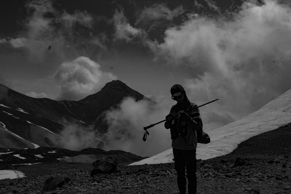 um homem com uma arma de pé em uma montanha
